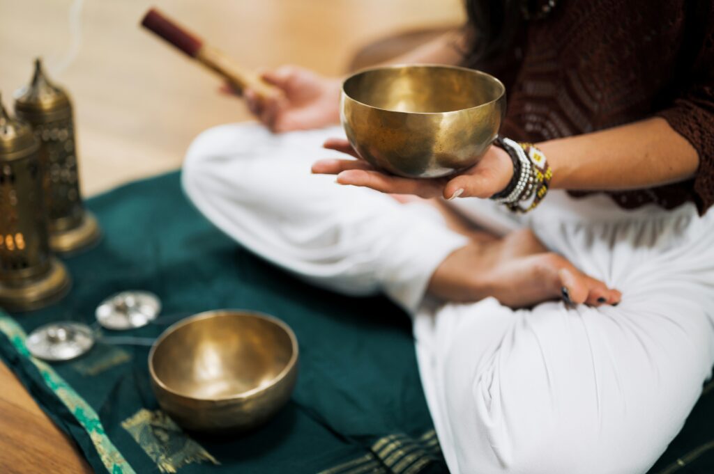 Hands holding a Himalayan singing bowl mid-ring in soft natural light
