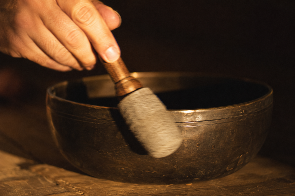 A felt mallet circling the rim of a Tibetan singing bowl to make it sing